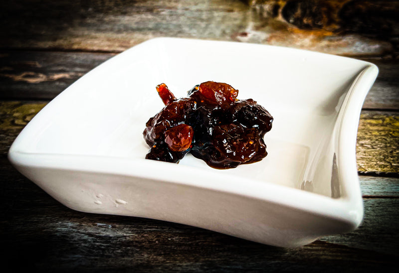  Nani's Achar Dried Fruit Pickle on served on white square platter. Cranberries, raisins, apricots and prunes preserve / compote
